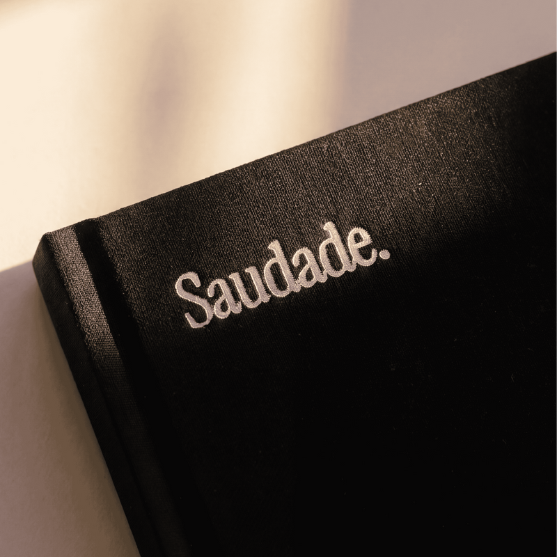 Saudade wordmark — top-left of every cover, foil-stamped